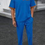 Trendbye wearing a blue outfit with brown accents standing on a dark surface.